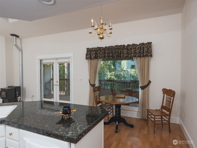 kitchen with a healthy amount of sunlight, white cabinetry, pendant lighting, and wood-type flooring