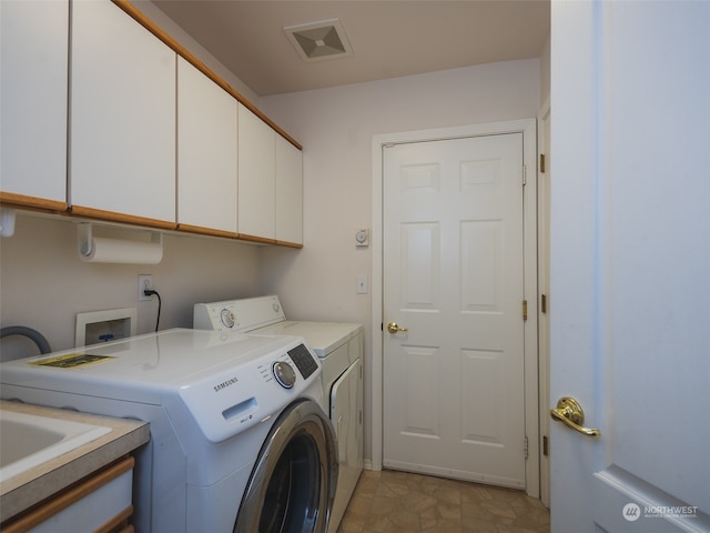 laundry room featuring washer and clothes dryer and cabinets