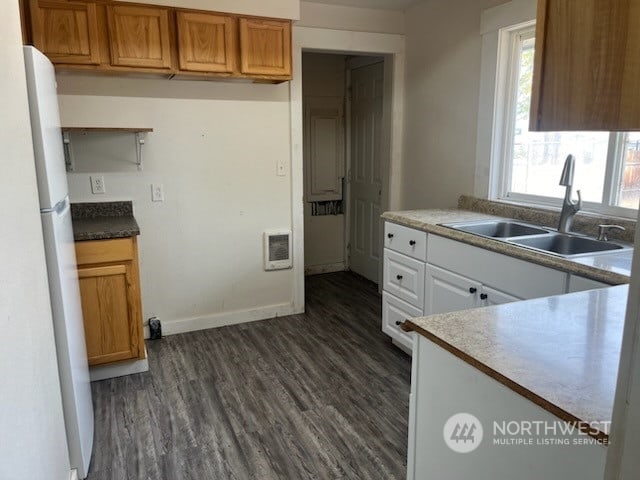 kitchen with white cabinets, heating unit, dark hardwood / wood-style flooring, white fridge, and sink