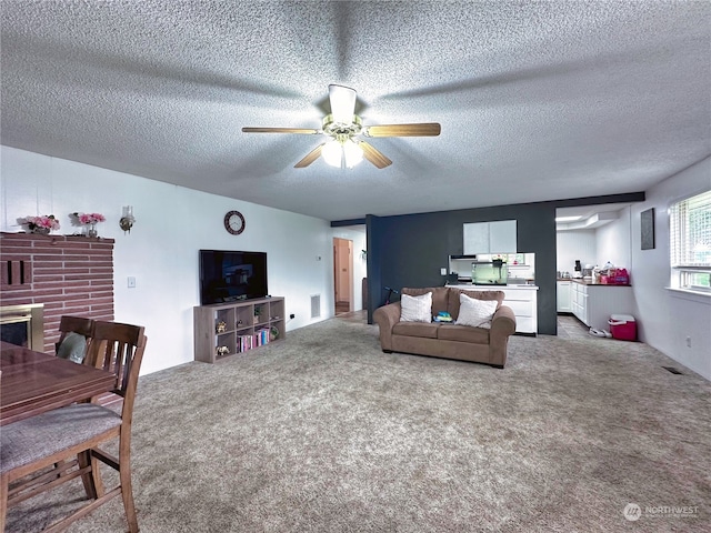 living room with a textured ceiling, carpet flooring, and ceiling fan