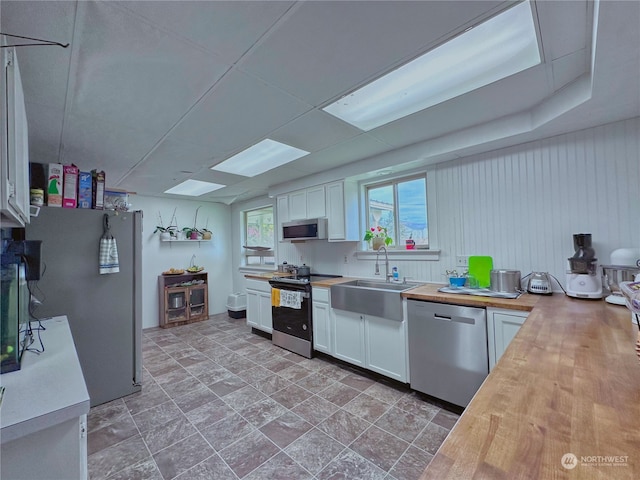 kitchen with sink, butcher block countertops, stainless steel appliances, and white cabinets