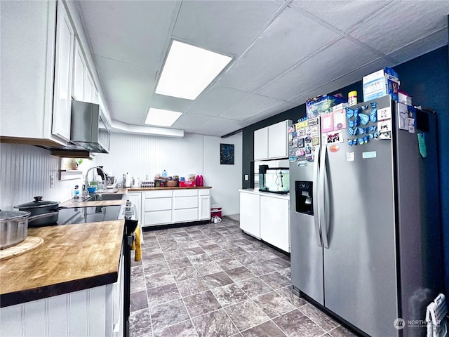 kitchen with white cabinetry, wood counters, stainless steel fridge with ice dispenser, and range