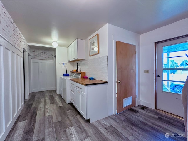 kitchen featuring washer and dryer, butcher block countertops, white cabinetry, hardwood / wood-style flooring, and decorative backsplash