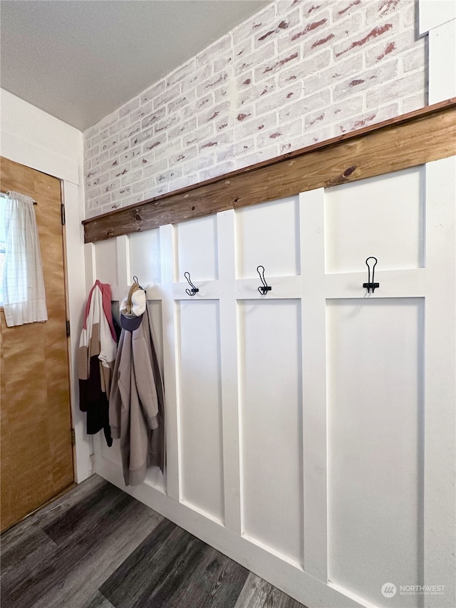 mudroom featuring brick wall and dark hardwood / wood-style flooring