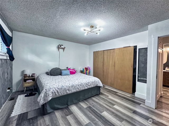 bedroom featuring a textured ceiling, hardwood / wood-style flooring, and an inviting chandelier