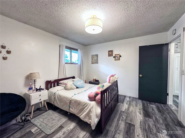 bedroom featuring a textured ceiling and dark hardwood / wood-style flooring