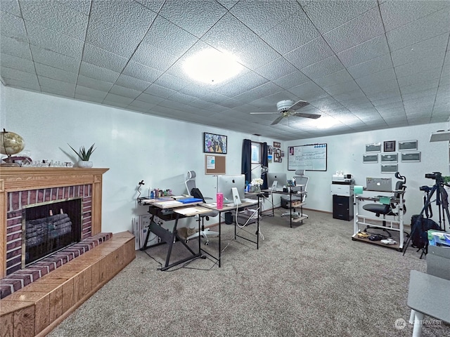 carpeted office space with a brick fireplace and ceiling fan