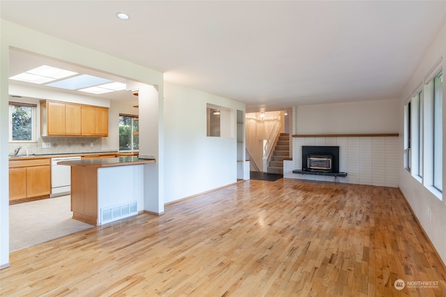 unfurnished living room with sink, a wood stove, and light hardwood / wood-style flooring