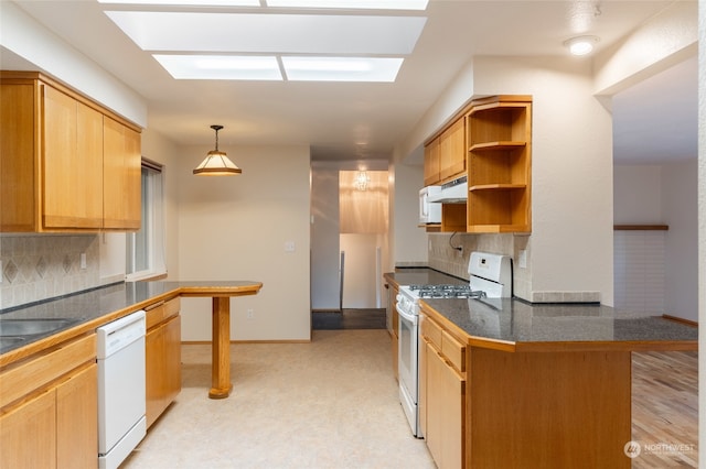 kitchen with white appliances, tasteful backsplash, kitchen peninsula, and hanging light fixtures