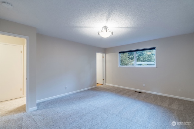 carpeted spare room featuring a textured ceiling