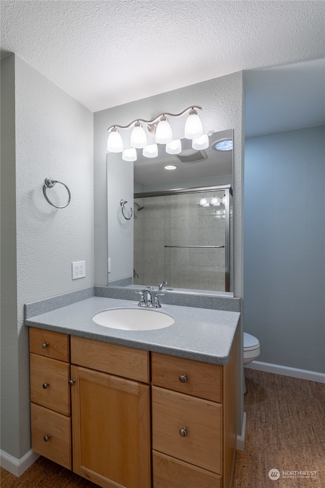 bathroom featuring a shower with door, a textured ceiling, wood-type flooring, toilet, and vanity