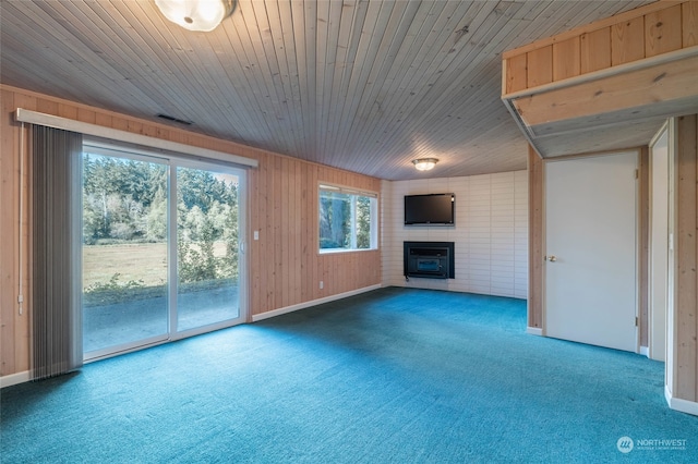 unfurnished living room featuring wooden walls, carpet flooring, and a healthy amount of sunlight