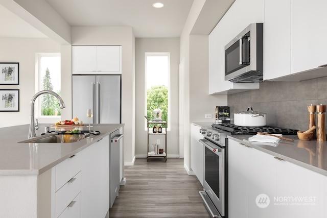 kitchen featuring white cabinets, tasteful backsplash, dark wood-type flooring, high quality appliances, and sink