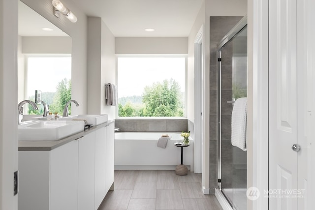 bathroom featuring vanity, plus walk in shower, and a wealth of natural light