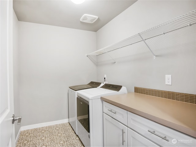 clothes washing area featuring washing machine and dryer and cabinets