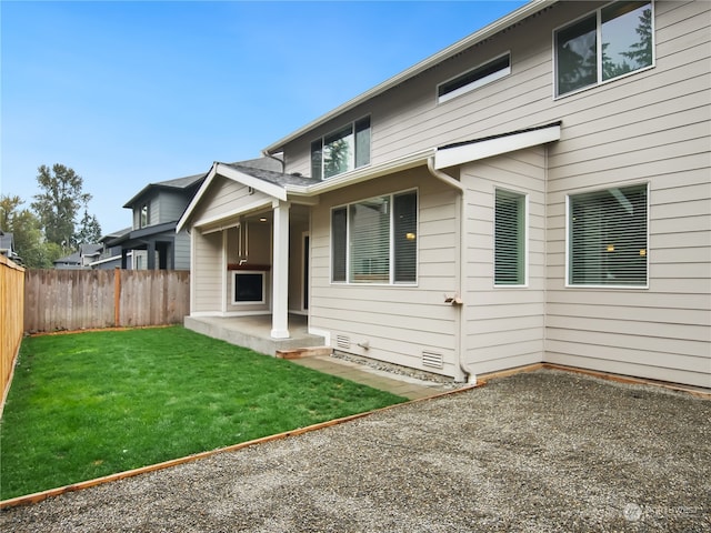 rear view of property featuring a yard and a patio area