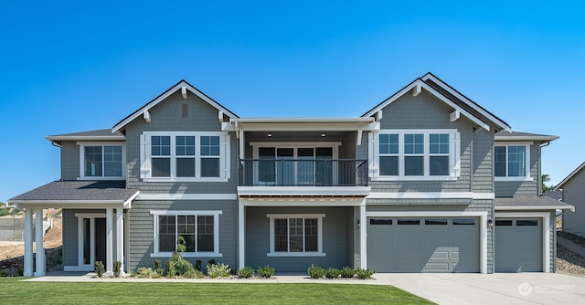 view of front facade featuring a balcony, a front lawn, and a garage