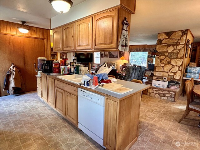 kitchen with kitchen peninsula, wood walls, sink, and white dishwasher