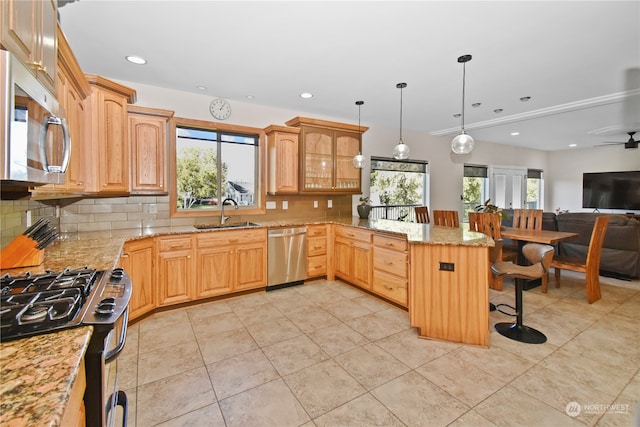 kitchen with kitchen peninsula, a breakfast bar area, appliances with stainless steel finishes, pendant lighting, and sink