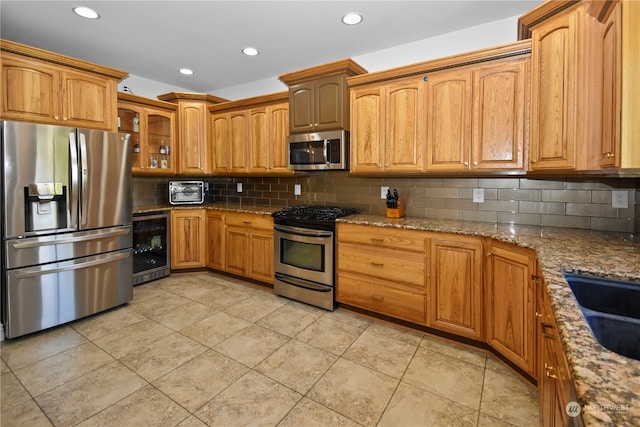 kitchen featuring tasteful backsplash, beverage cooler, appliances with stainless steel finishes, light tile patterned flooring, and stone countertops