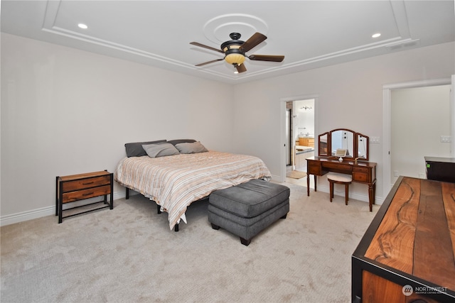 bedroom featuring connected bathroom, ceiling fan, light carpet, and a tray ceiling