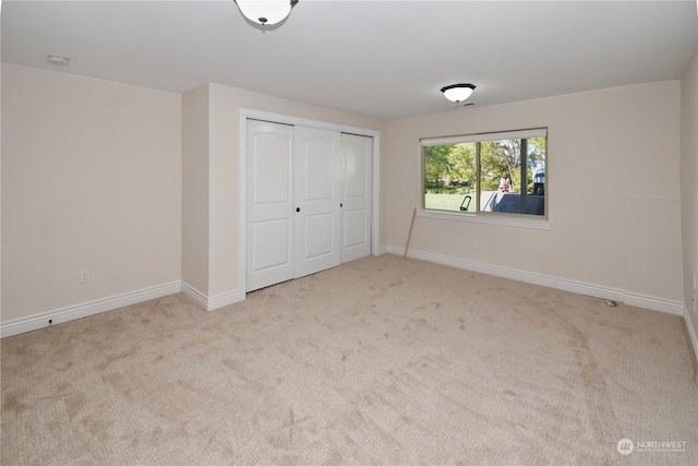 unfurnished bedroom featuring a closet and light carpet