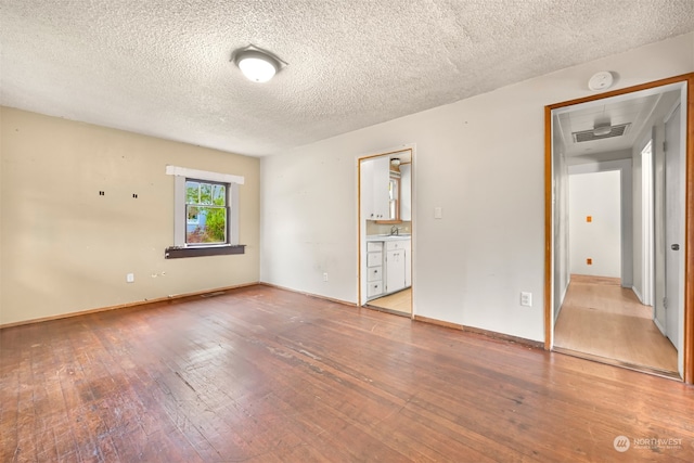 unfurnished room with a textured ceiling, sink, and light wood-type flooring