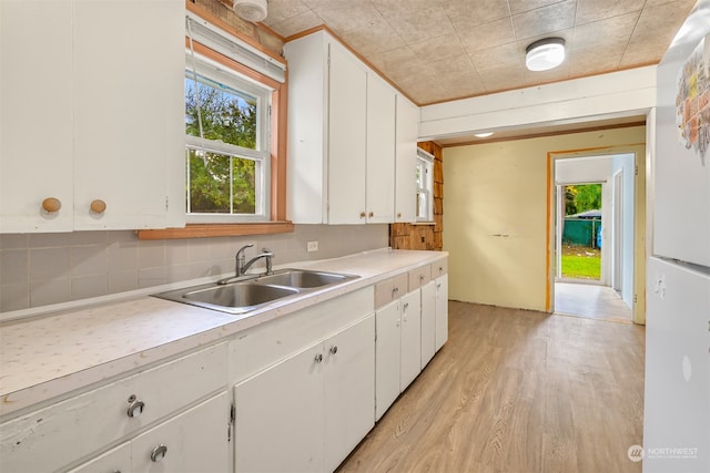 kitchen with sink, white cabinetry, decorative backsplash, and light wood-type flooring