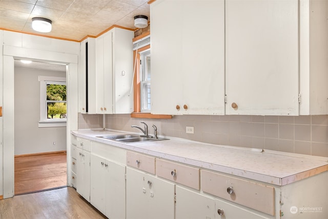 kitchen featuring white cabinets, tasteful backsplash, sink, and light wood-type flooring