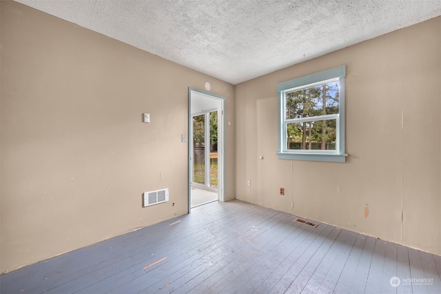 unfurnished room with hardwood / wood-style flooring and a textured ceiling