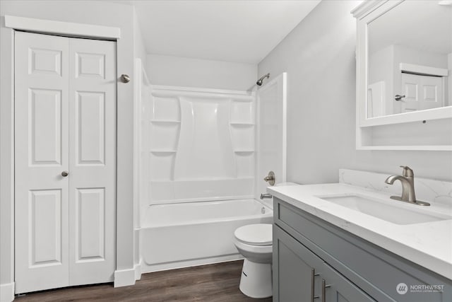 full bathroom with hardwood / wood-style floors, vanity, washtub / shower combination, and toilet