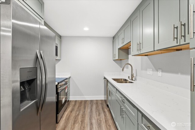 kitchen with gray cabinets, appliances with stainless steel finishes, sink, and light hardwood / wood-style flooring