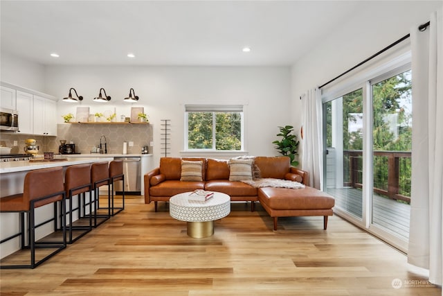 living room featuring sink, a wealth of natural light, and light wood-type flooring