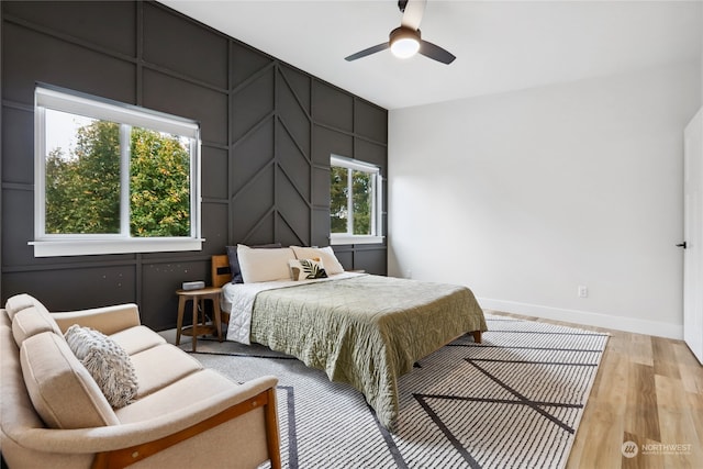 bedroom featuring ceiling fan, multiple windows, and light hardwood / wood-style flooring