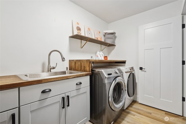 washroom featuring sink, separate washer and dryer, light wood-type flooring, and cabinets