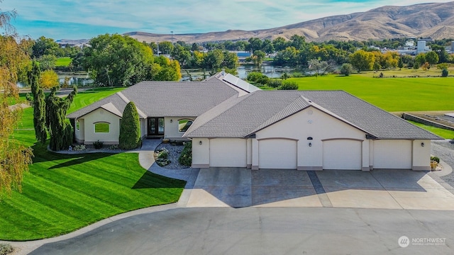 view of front facade featuring a mountain view, a front lawn, and a garage