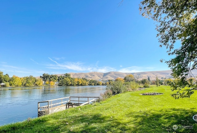 dock area with a yard and a water and mountain view