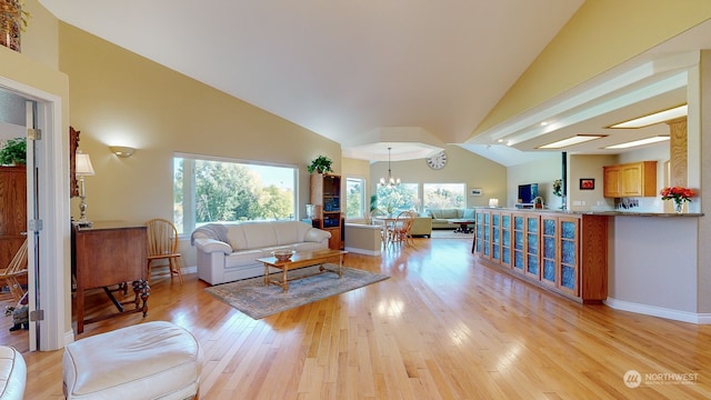 living room featuring light hardwood / wood-style floors, a chandelier, and vaulted ceiling