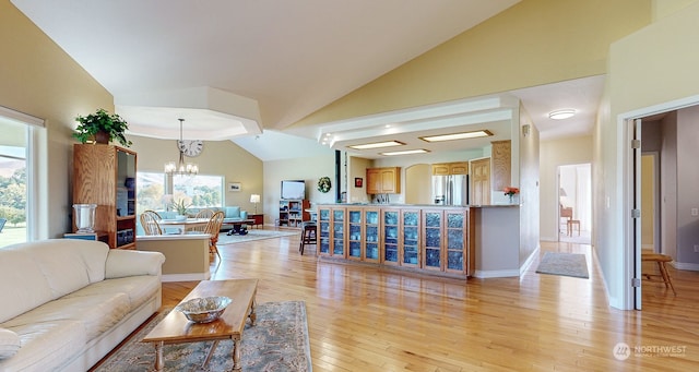 living room with light hardwood / wood-style flooring, high vaulted ceiling, and a notable chandelier