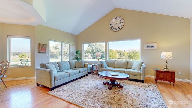 living room featuring high vaulted ceiling, a healthy amount of sunlight, and light wood-type flooring