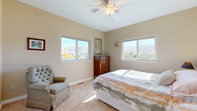 carpeted bedroom with multiple windows and ceiling fan