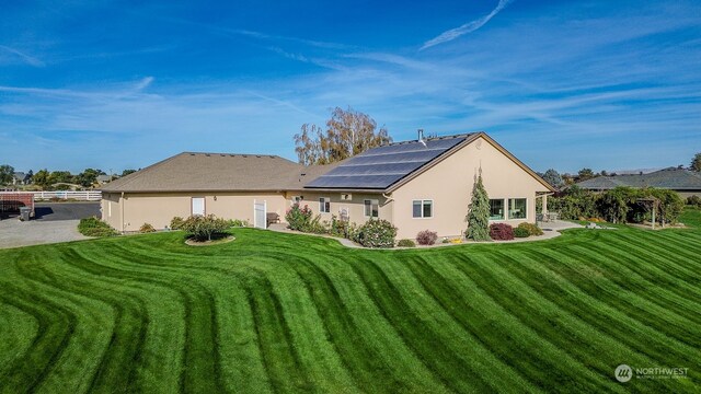 back of house with solar panels and a yard