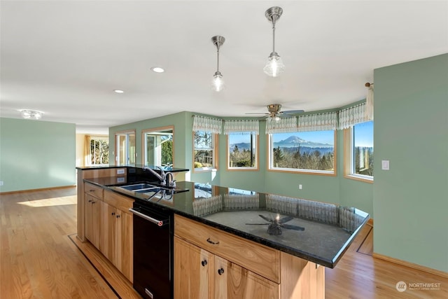 kitchen featuring sink, hanging light fixtures, black dishwasher, light hardwood / wood-style floors, and an island with sink