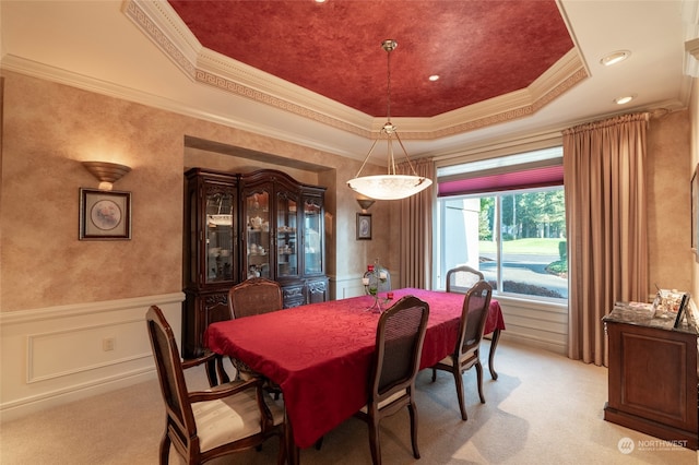dining space featuring light carpet, ornamental molding, and a tray ceiling