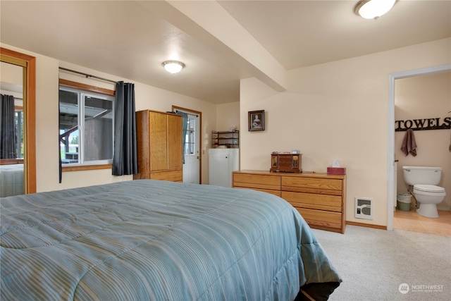 bedroom with ensuite bathroom, heating unit, and light colored carpet