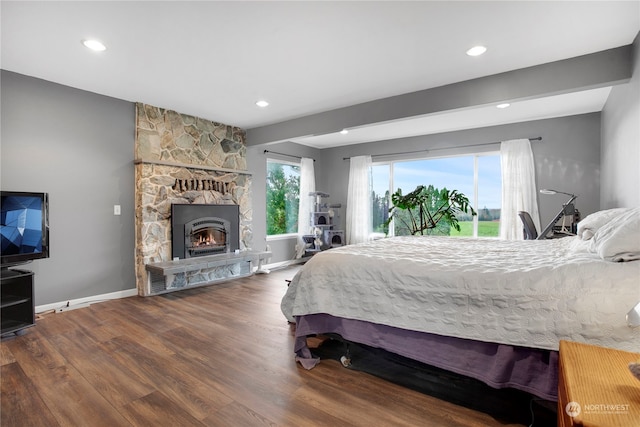 bedroom featuring a stone fireplace and dark wood-type flooring