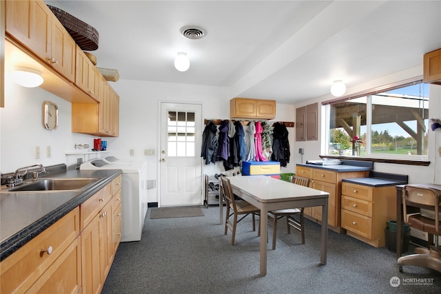 kitchen with sink, light brown cabinetry, washer and clothes dryer, and dark colored carpet