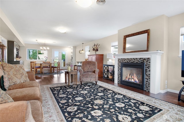 living room featuring an inviting chandelier, hardwood / wood-style floors, and a tile fireplace