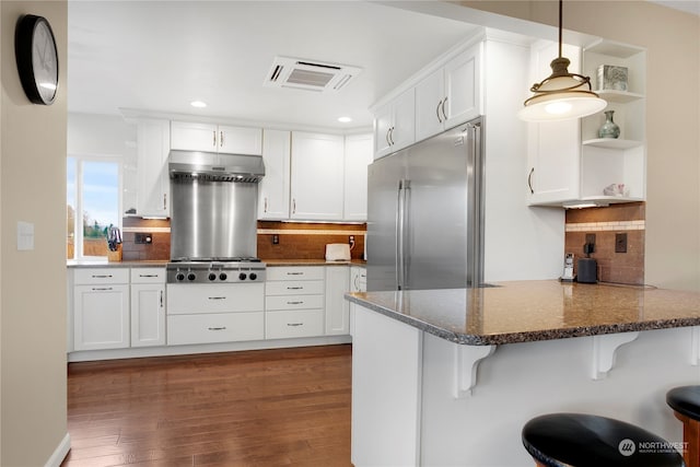 kitchen with kitchen peninsula, tasteful backsplash, a breakfast bar, dark wood-type flooring, and stainless steel appliances