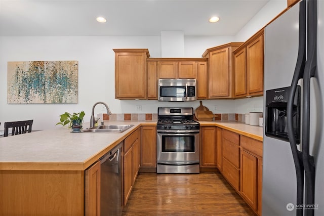 kitchen featuring sink, appliances with stainless steel finishes, dark hardwood / wood-style flooring, and kitchen peninsula